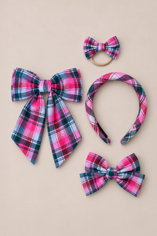 Showcased on a neutral background, Ivy City Co’s “Hair Bows in Vibrant Plaid” set includes four pink plaid accessories: a statement large bow with long tails, a petite clip-on bow, a matching headband, and a charming bow hair tie—perfect festive accents for the holidays.