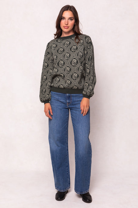 Woman wearing a patterned sweater and blue jeans on a white background