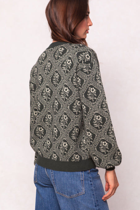 Person wearing a patterned jacket and blue jeans on a white background