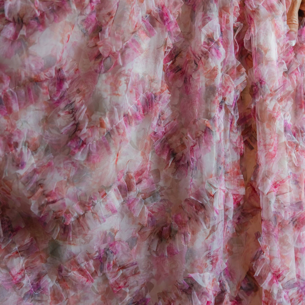 Close-up of sheer, ruffled fabric from Ivy City Co's Florentina Dress in Alluring Floral, showcasing pink, red, and white blooms. Lightweight layers give a textured, delicate look for timeless femininity.