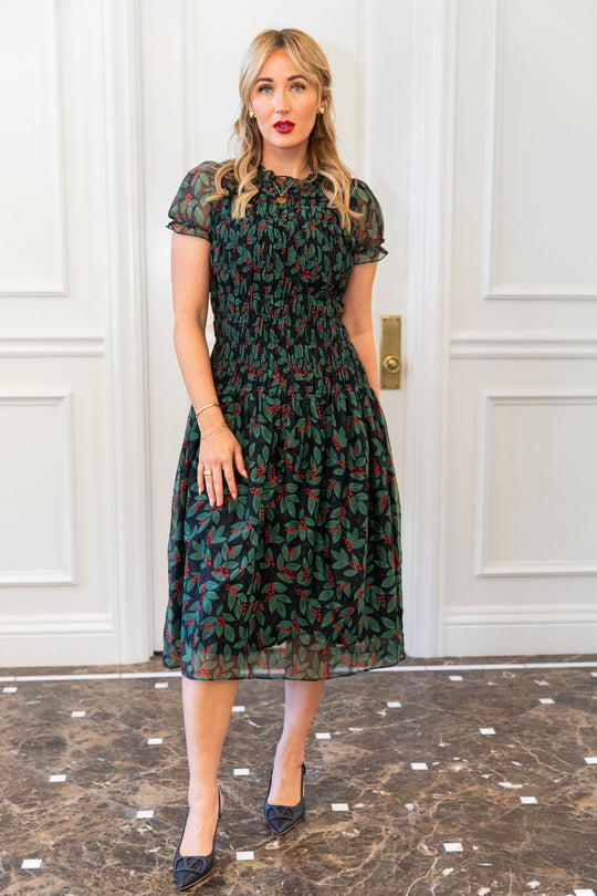 Woman wearing a patterned dress standing in front of a white paneled door.