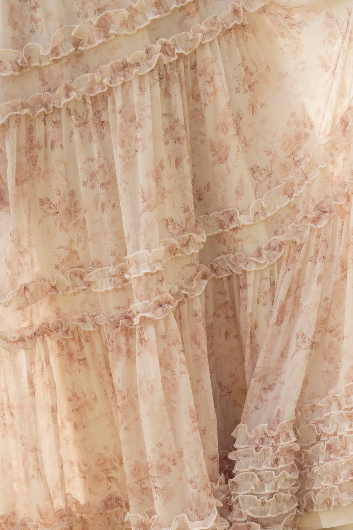 Close-up of the Geneva Dress in Banana Creme Aquarelle Fleur by Ivy City Co, featuring light pink, sheer fabric with a delicate floral pattern and layered ruffles for a soft, flowy, romantic, vintage-inspired look.