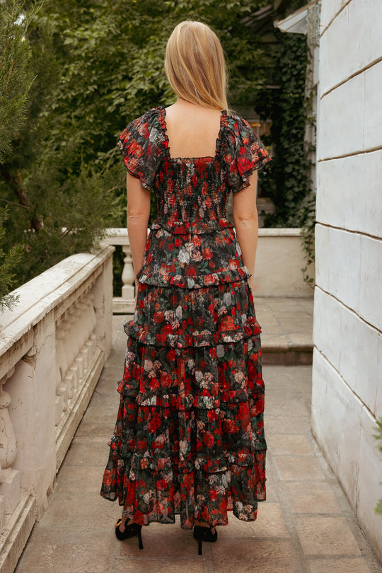 Woman in a floral dress walking on a stone path with greenery in the background