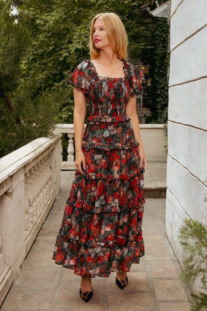 Woman in a floral dress standing on a stone pathway with greenery in the background