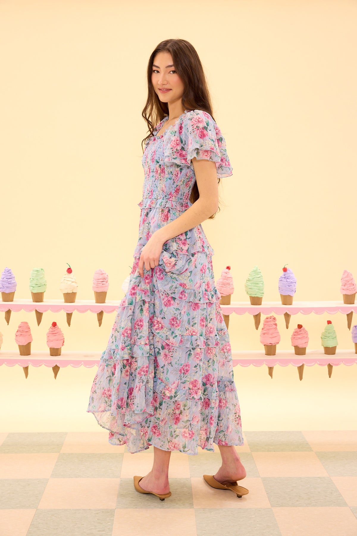 Woman wearing a floral dress standing in front of an ice cream cone display.