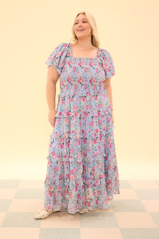 Woman wearing a floral dress on a checkered floor with a beige wall background