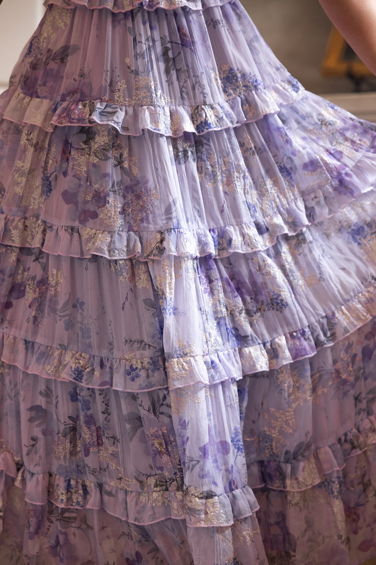 A close-up of the Winnie Dress in Lavender Aquarelle Fleur by Ivy City Co, featuring tiered ruffles, floral chiffon, and sheer layers—ideal for a spring wedding or as a chic, maternity-friendly choice.