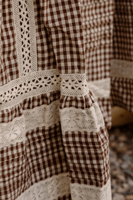 Close-up of brown and white hickory gingham fabric with intricate white lace details, showcasing the various patterns and textures from the Ivy City Co Mini Palermo Dress in Hickory Gingham—a charming cotton-blend dress for girls. The background is slightly out of focus.