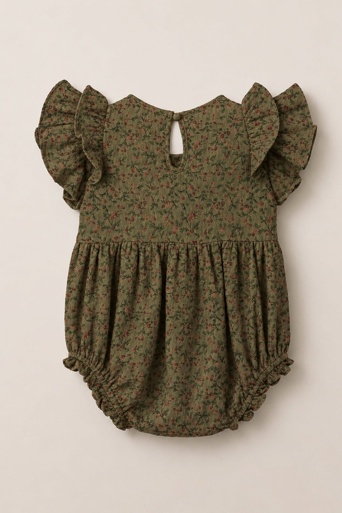 The Ivy City Co Baby Hattie Romper in Woodland Floral features an olive green base adorned with a small floral print, flutter sleeves, a gathered waist, elastic leg openings, and a back button keyhole closure. Crafted from soft cotton, this romper is perfect for your little one’s everyday adventures.