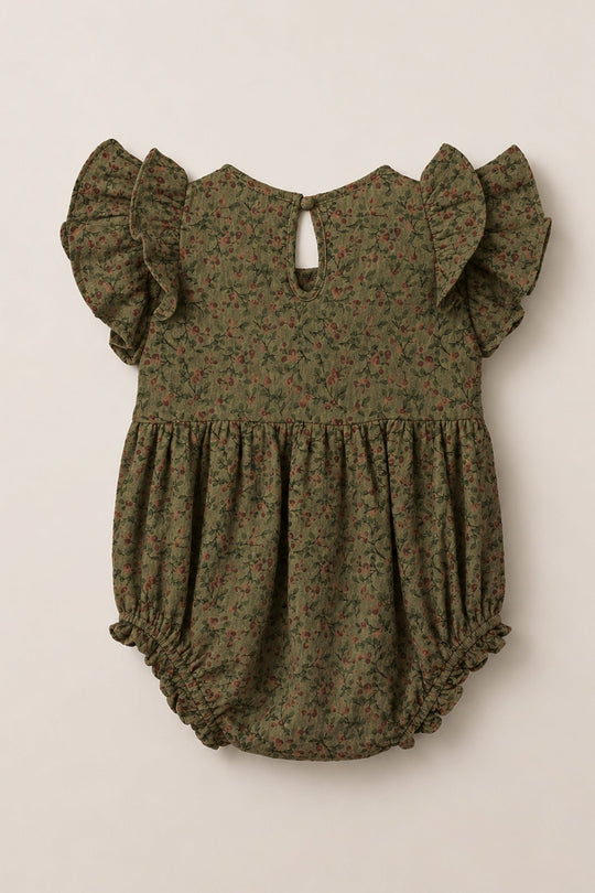 The Ivy City Co Baby Hattie Romper in Woodland Floral features an olive green base adorned with a small floral print, flutter sleeves, a gathered waist, elastic leg openings, and a back button keyhole closure. Crafted from soft cotton, this romper is perfect for your little one’s everyday adventures.