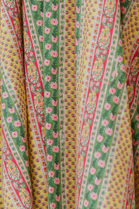 A close-up of the Zaza Dress by Ivy City Co, made with Liberty Fabric, shows vertical green, yellow, and pink stripes adorned with intricate floral and geometric patterns featuring repeating small flower motifs.