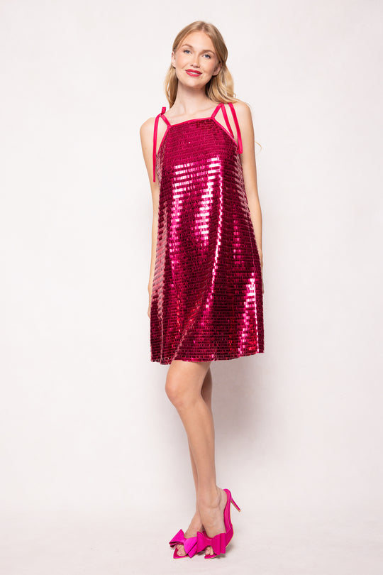 Woman wearing a red sequin dress with pink shoes on a white background