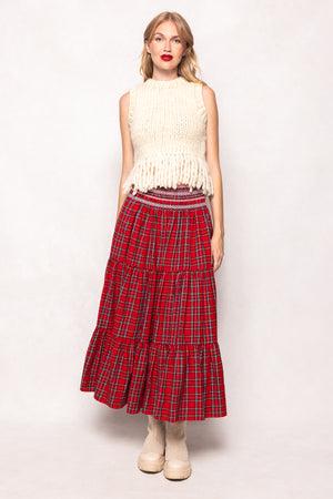 Woman wearing a white sleeveless top and red plaid skirt on a white background