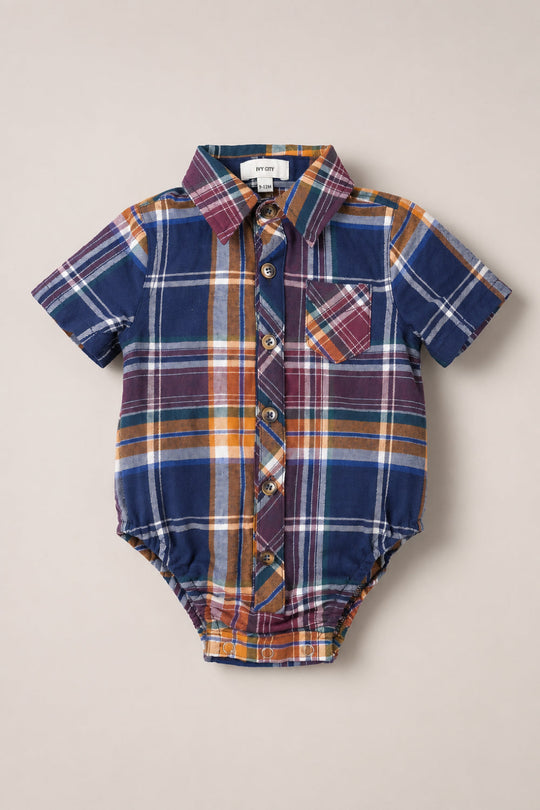 The Ivy City Co Baby Boy James Romper in Midnight Plaid, featuring short sleeves, a blue, orange, and burgundy plaid pattern, front buttons, a chest pocket, and a shirt collar, is laid flat on a neutral background.