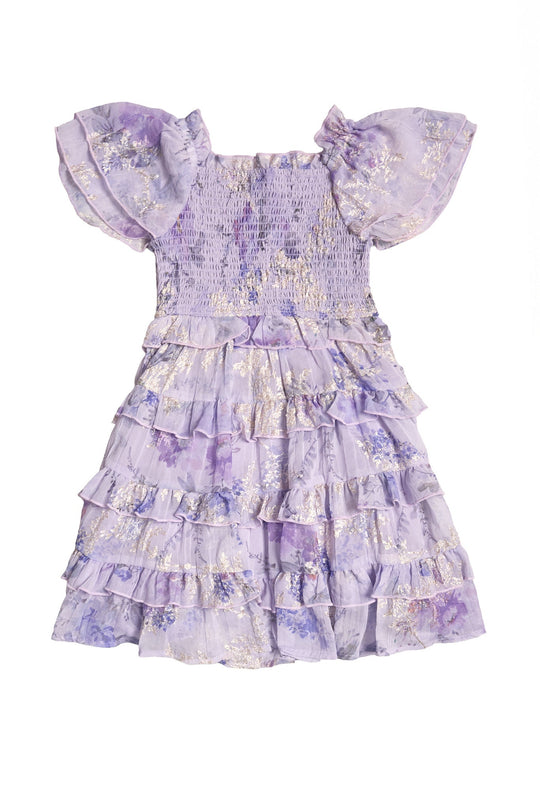 The Mini Winnie Dress in Lavender Aquarelle Fleur by Ivy City Co is a charming girls’ spring dress with short sleeves, ruffled tiered layers, and a smocked bodice. Adorned with a delicate floral pattern and subtle gold detailing, this elegant dress perfectly blends charm and sophistication.