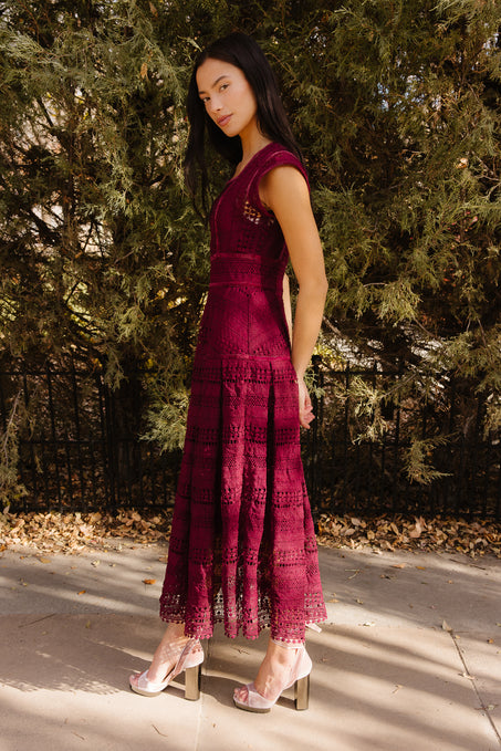 Girl in a red dress standing outdoors in front of trees