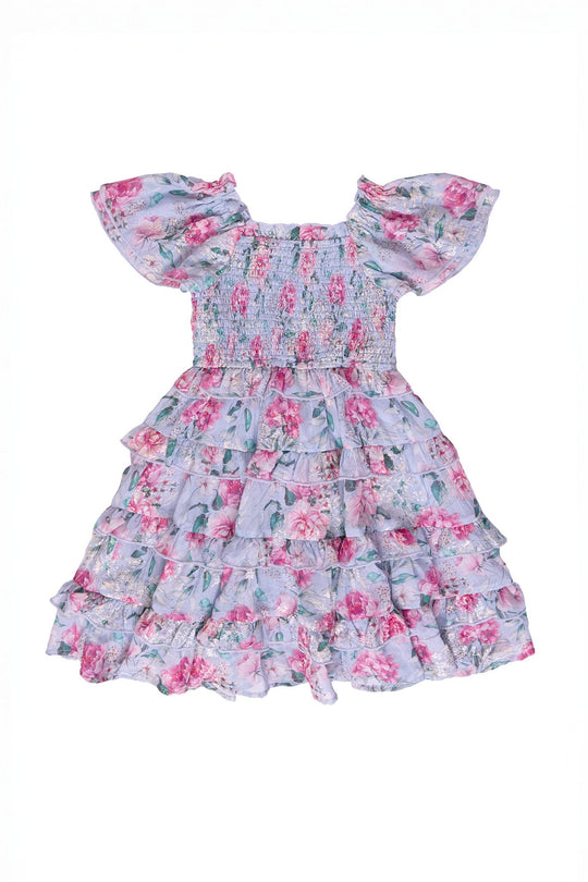 The Mini Winnie Dress in Peony Blossoms by Ivy City Co is a light purple, short-sleeve dress featuring a smocked bodice and a tiered ruffle skirt. Pink and green peony floral patterns cover the entire dress, shown against a white background.