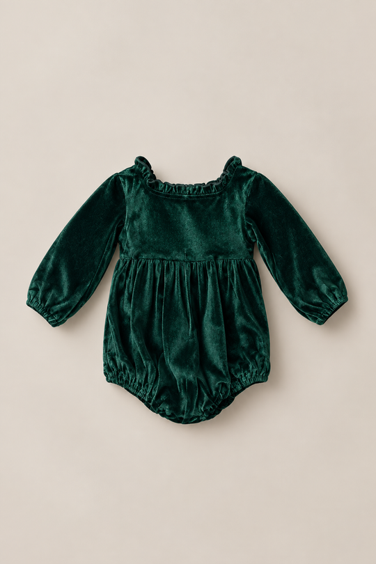 The Ivy City Co Baby Cypress Romper in Green Velvet features long sleeves, delicate ruffle detailing at the neckline, a gathered waist, and elastic leg openings, shown against a light beige background.