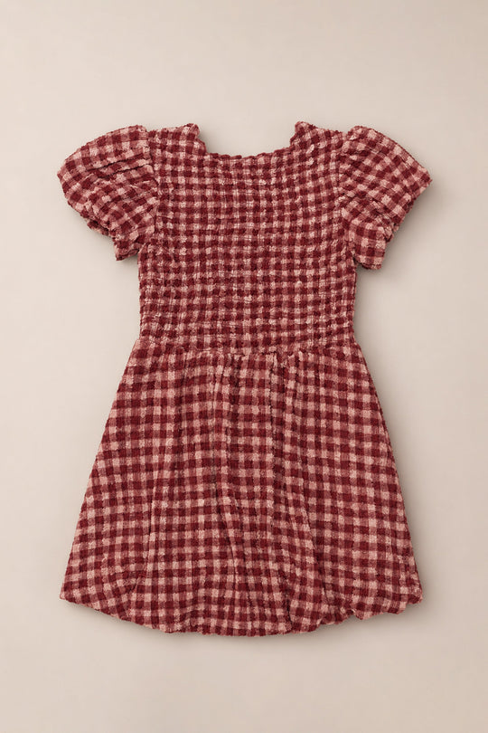 Mini Tori Dress in Cranberry Popcorn Plaid by Ivy City Co, featuring short sleeves, a smocked bodice, and a flared skirt, laid flat on a light background.