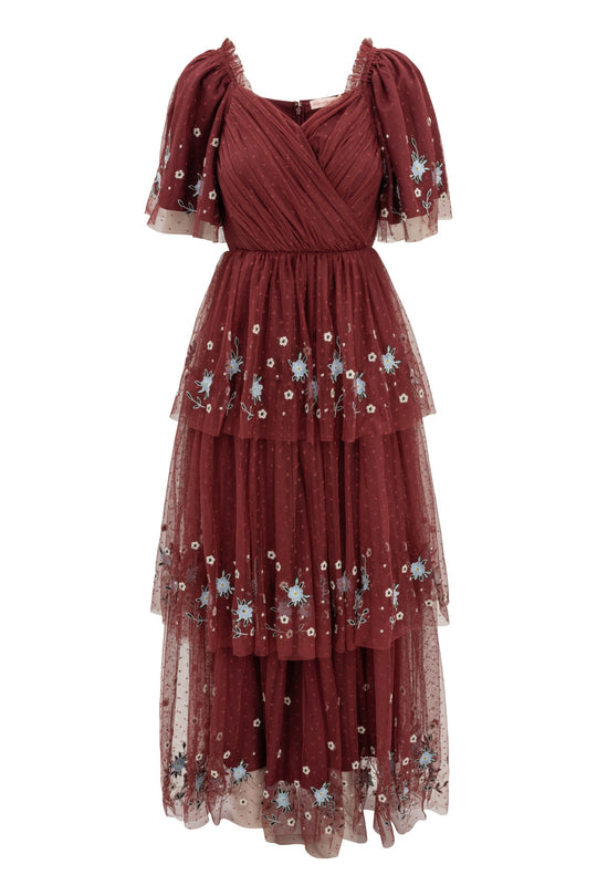 The Mabel Dress in Burgundy by Ivy City Co features short puff sleeves and exquisite blue and white floral embroidery on rich maroon tulle. This elegant embroidered dress boasts a fitted bodice and a flowy, tiered skirt, offering a beautifully layered look.