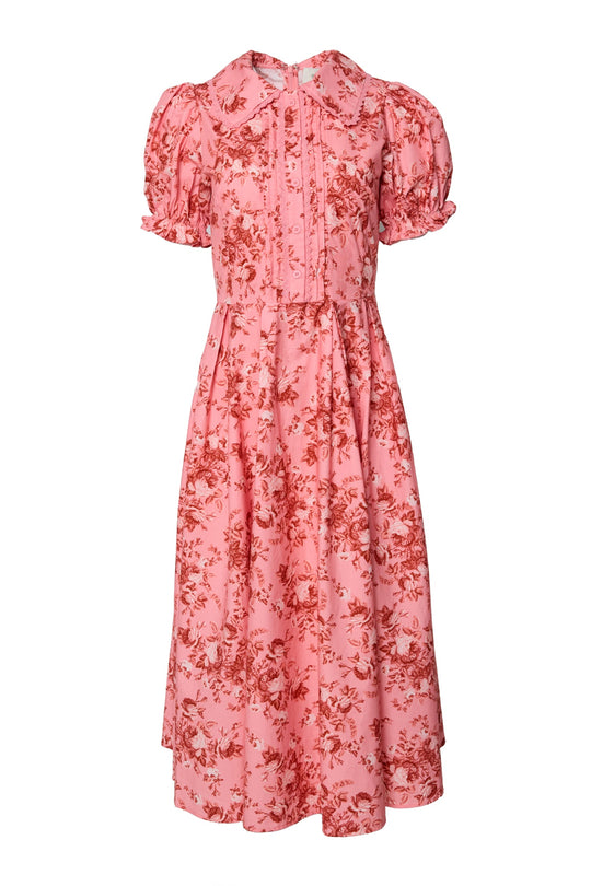 The Sophia Dress in Desert Heritage Rose by Ivy City Co is a pink floral midi dress adorned with a bold red Desert Heritage Rose print. It features short puff sleeves, a ruffled collar, button detailing down the front, a fitted bodice, and a gathered skirt, blending timeless elegance with romantic charm.