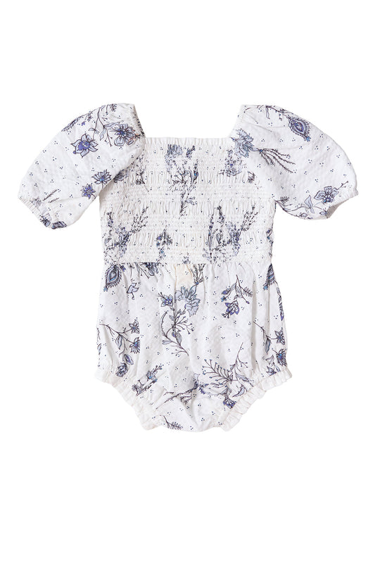 Dress your little one in the Baby Roselyn Romper in Blue Enchanted Floral by Ivy City Co, featuring puffed short sleeves, a shirred bodice, elastic leg openings, and a charming blue floral pattern on soft white fabric. This delicate romper can be paired as part of an adorable Mom & Me set.