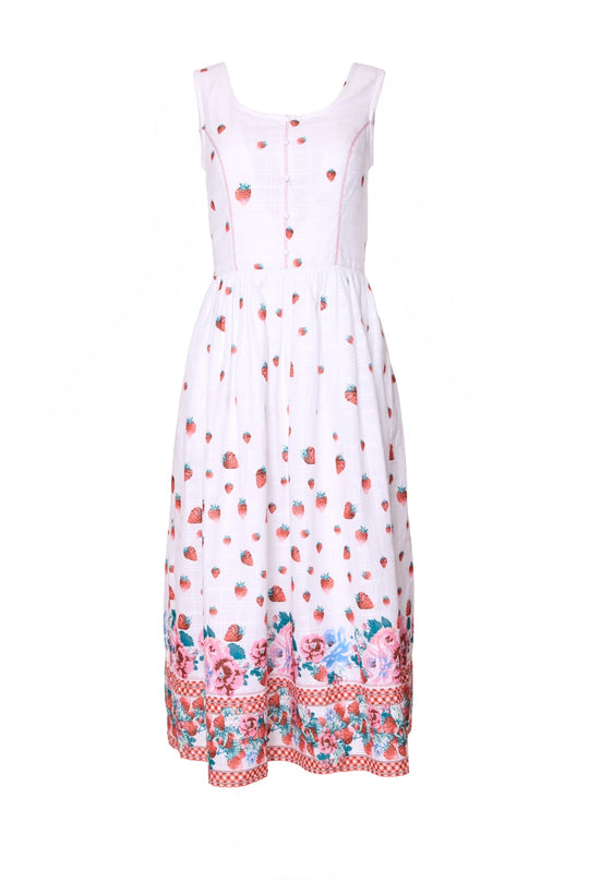 The Sadie Dress in Strawberry Vintage Tier by Ivy City Co is a sleeveless white cotton summer dress featuring a strawberry print, a fitted bodice, and a skirt accented with pink, blue, and red floral and checkered patterns near the hem.