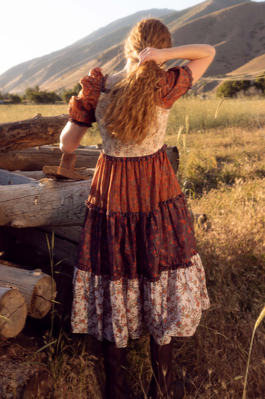 Person in a rustic setting with mountains and logs