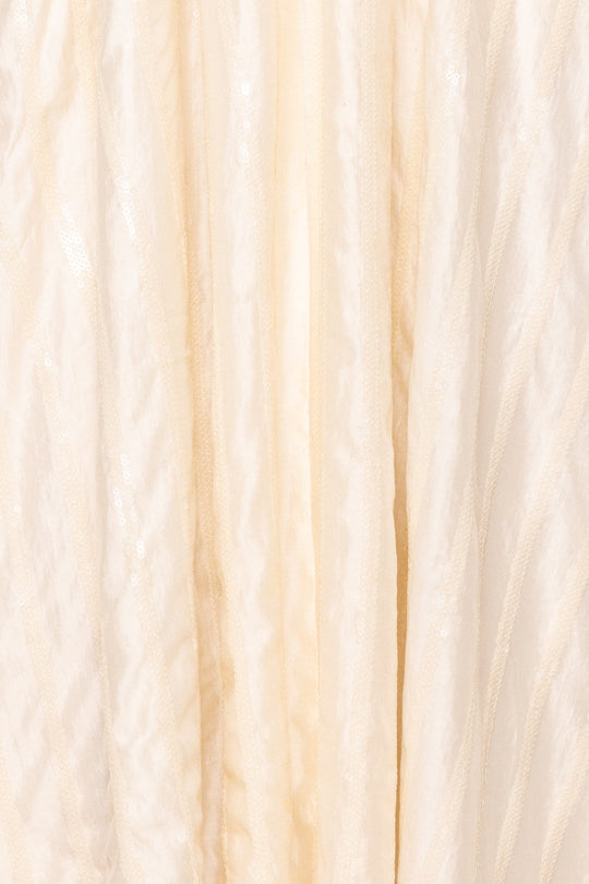 Close-up of the creamy white, pleated, semi-sheer fabric with a subtle shine found on the Ivy City Co Tindra Dress in Cream Sequin, draped in soft vertical folds—a detail that enhances this elegant midi dress designed to be both nursing friendly and maternity friendly.