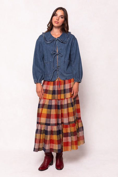Woman wearing a denim jacket and plaid skirt on a white background