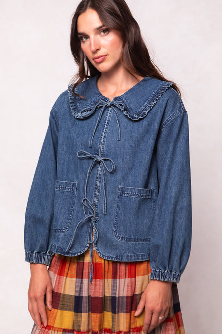 Woman wearing a blue denim jacket over a plaid dress on a white background