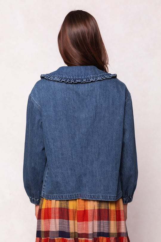 Person wearing a blue denim jacket and plaid skirt on a plain background