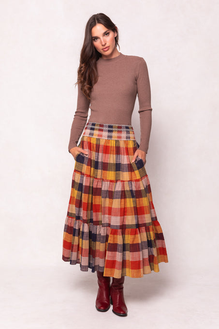 Woman wearing a plaid skirt and brown top on a white background