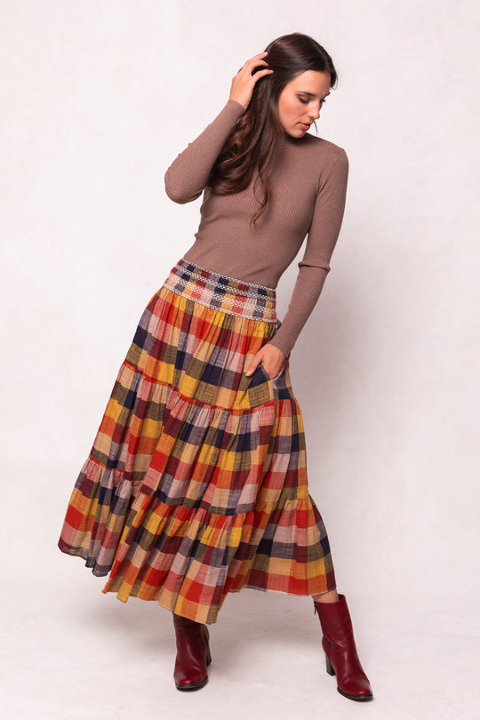 Woman wearing a plaid skirt and brown top on a white background