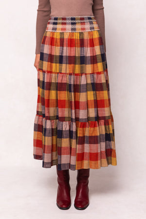 Plaid skirt with autumn colors worn by a person on a white background