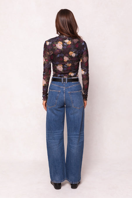 Person wearing a floral top and blue jeans on a white background