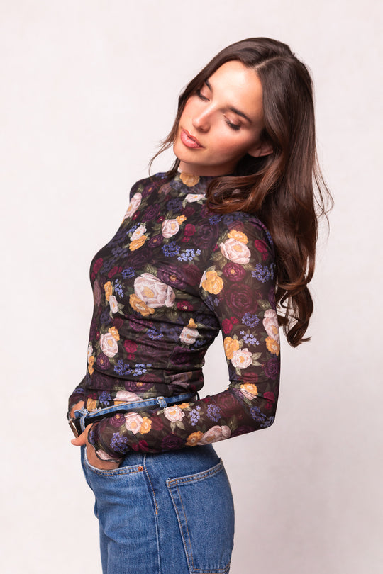 Woman wearing a floral long-sleeve top and jeans on a white background