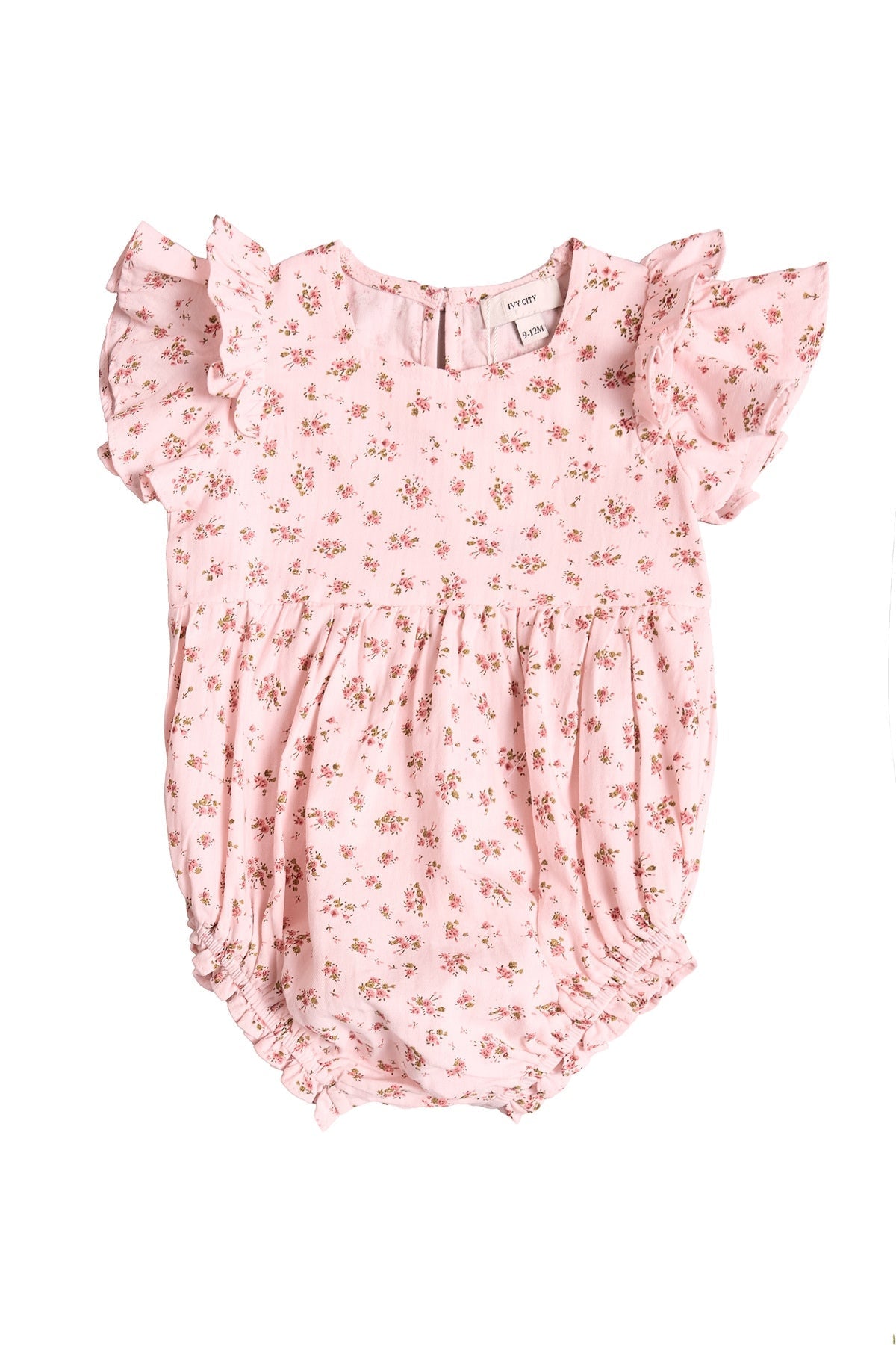 The Ivy City Co Baby Hattie Romper in Madeline Pink features short ruffled sleeves, a delicate small floral print, a gathered waist, and elastic leg openings—perfect for a first birthday outfit and shown on a white background.