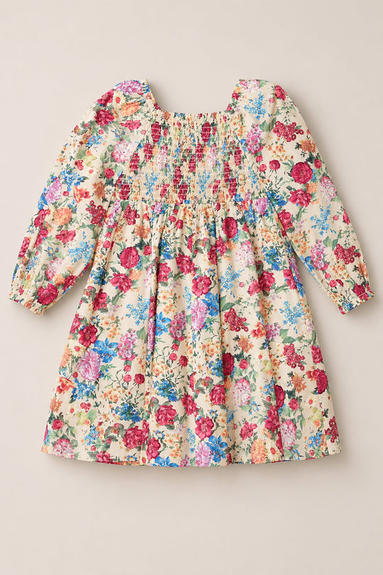 The Mini Adelpha Dress in Autumn Amity Floral by Ivy City Co features long sleeves and a vibrant floral print on a light background, with a smocked bodice and gathered fabric for a loose, flowing silhouette. Charming balloon sleeves add an extra touch of whimsy to this children’s dress.
