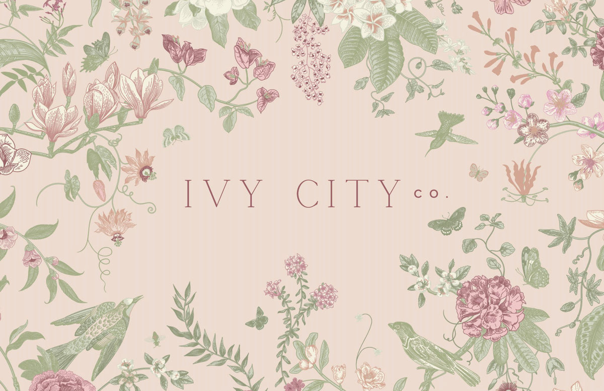 A pastel pink Ivy City Co Gift Card ($10-$250) features the brand name framed by floral, leaf, butterfly, and bird illustrations in soft pink and green tones—making it a dreamy gift.