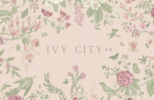 Delicate floral and bird illustrations in soft pastel tones frame “Ivy City Co” on a pale pink background—a charming design for the Ivy City Co Gift Card ($10-$200), available with convenient email delivery.