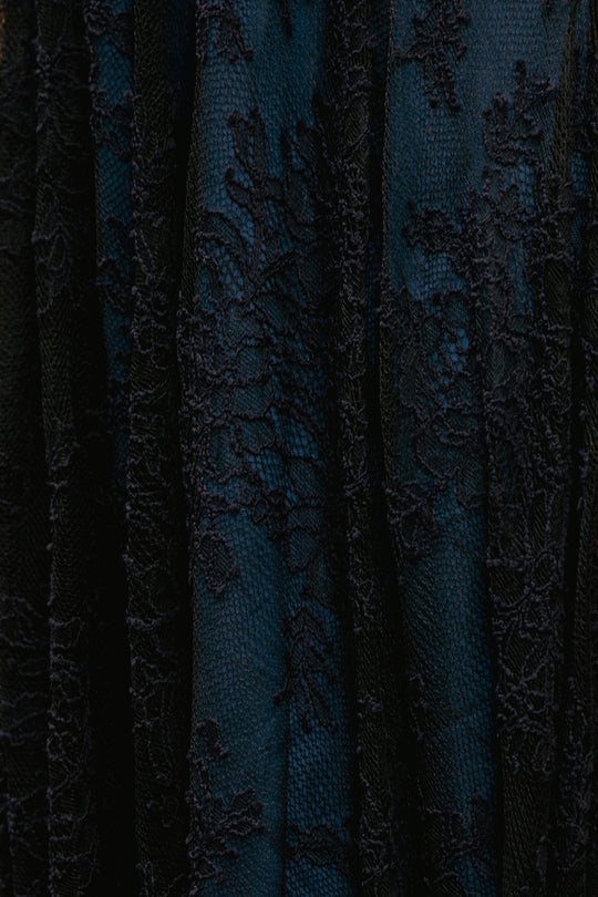 Close-up of the Isadora Dress in Navy & Black by Ivy City Co, showcasing its elegant dark blue fabric with a detailed black lace floral overlay and soft, flowing folds; this stylish maternity-friendly dress combines sophistication with comfort.