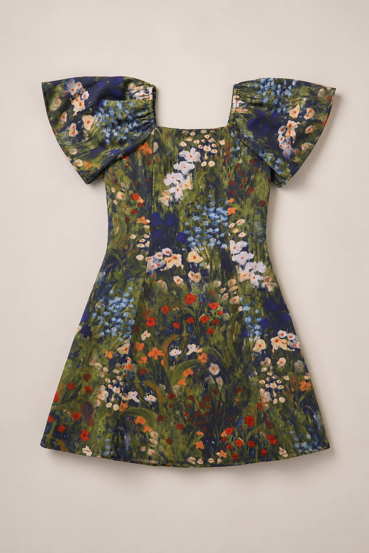 Introducing the Ivy City Co Teen Blakely Flutter-Sleeve Dress in Impressionist Bloom: this short-sleeve dress features flared flutter sleeves and a square neckline, adorned with a vibrant floral print of red, blue, white, and orange blooms against a green background. Displayed laid flat on a beige surface, it’s the perfect addition to your fall wardrobe.