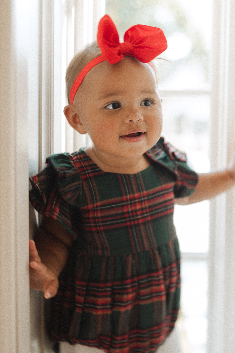 Plaid baby girl romper with ruffled details on sleeve in a window