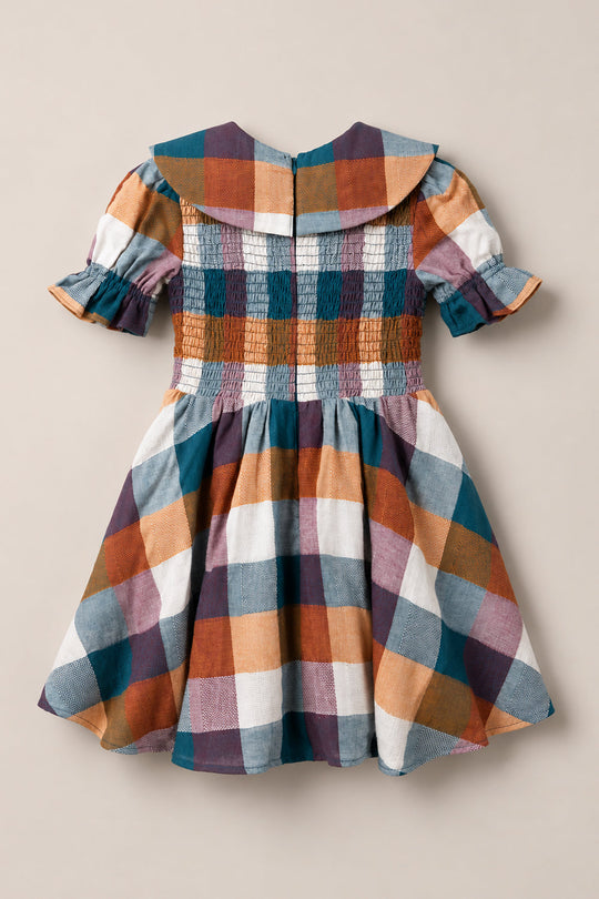 The Mini Alice Dress in Maize Gingham by Ivy City Co is a plaid dress featuring puffed half sleeves, a wide collar, and a fitted smocked bodice. Its design showcases large gingham checks in shades of blue, orange, burgundy, and white.