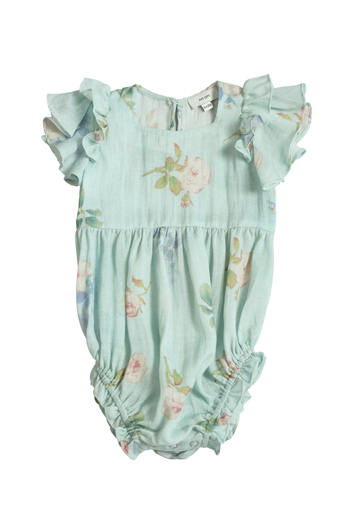 The Ivy City Co Baby Hattie Romper in Roselyn Blue features short, ruffled sleeves and a pastel floral pattern on a light blue background, with gentle gathering at the legs and waist. Displayed on a white background, this darling piece is perfect for coordinating mommy-and-me outfits.