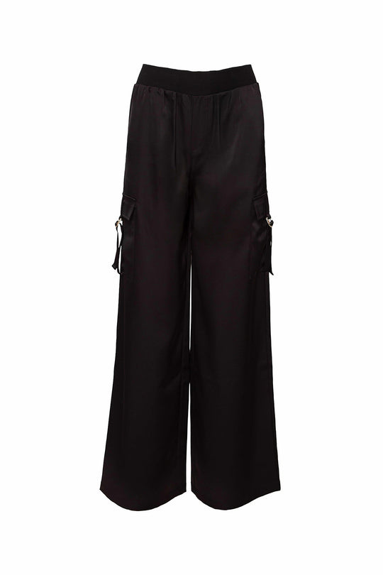 The Shay Satin Pants in Black by Ivy City Co are wide-leg cargo pants with a loose fit, designed with an elastic waistband and side flap pockets, displayed on a plain white background.