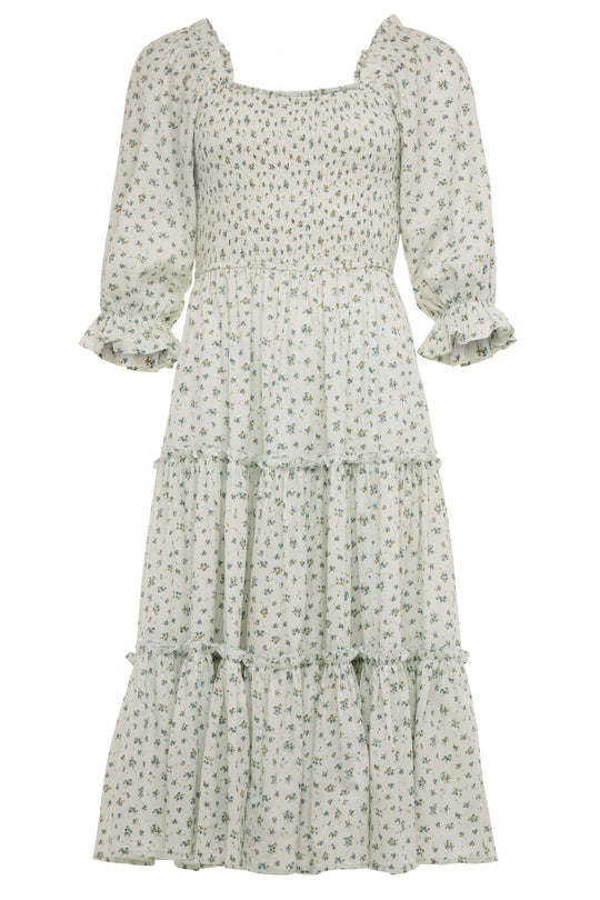 The Madeline Dress in Blue by Ivy City Co is a blue, long, tiered floral midi dress with a smocked bodice, three-quarter puff sleeves with ruffled cuffs, and a square neckline—an effortlessly maternity friendly style.