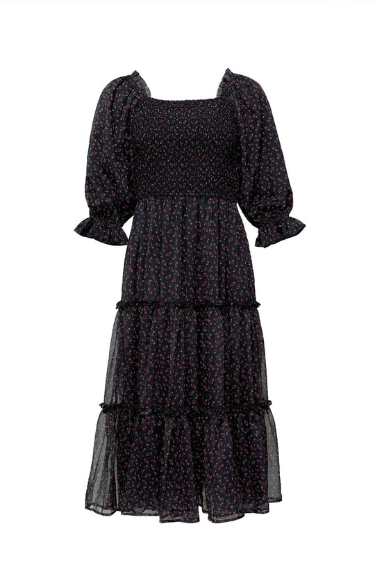 The Madeline Dress in Black Ditsy Floral by Ivy City Co is a mid-length maternity-friendly dress featuring a small ditsy floral print, puffed elbow-length sleeves with ruffled cuffs, a smocked bodice, and a tiered skirt. Designed with timeless elegance, it is finished with a classic square neckline.
