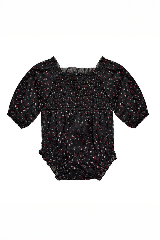 The Ivy City Co Baby Madeline Romper in Black Ditsy Floral features a delicate red and white ditsy print, puffed half-sleeves, a smocked bodice, and ruffled elastic leg openings, beautifully laid flat on a white background.